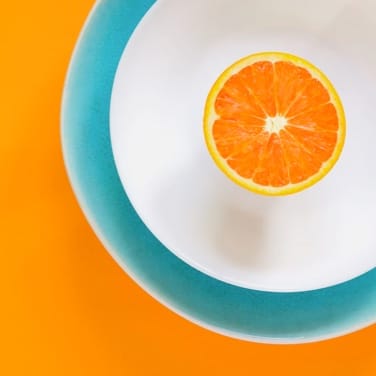 orange on a white plate on a green plate on table