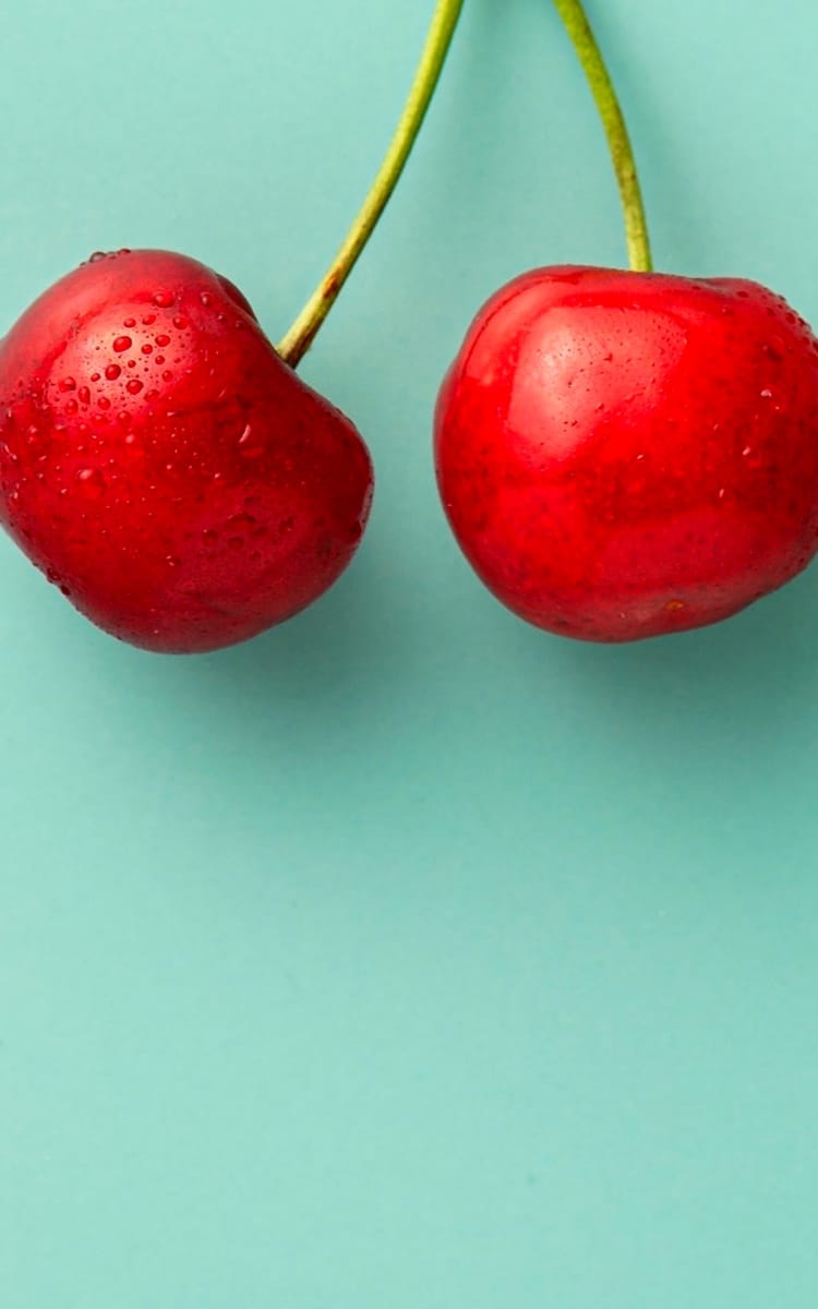 Pair of cherries on green background